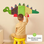 Child playing with a colorful dinosaur-shaped wall toy.