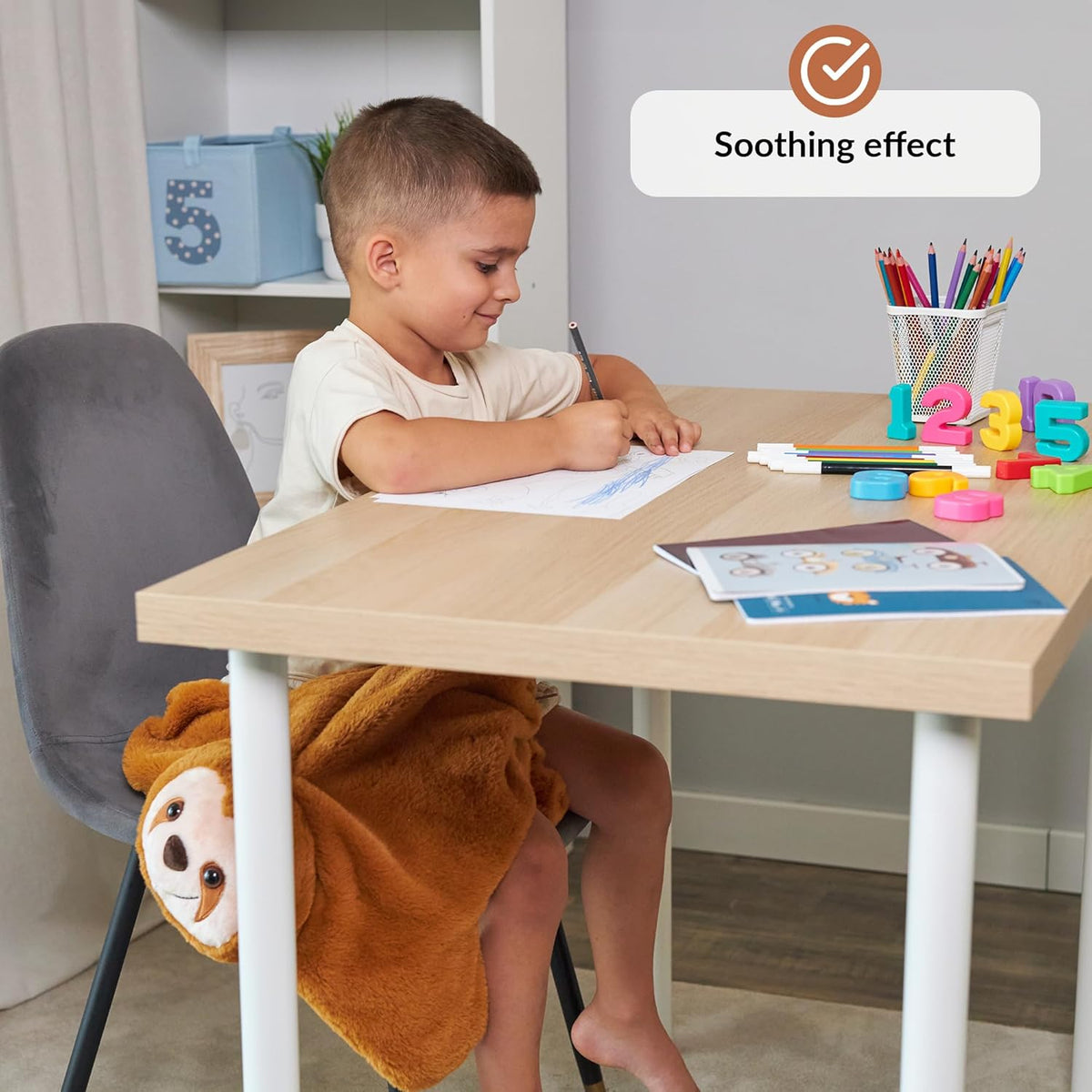 Child sitting at a desk with educational materials and a weighted lap sloth, with a 'Soothing effect' label.