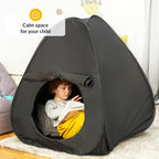 Child reading inside a black pop-up sensory tent labeled 'Calm space for your child' in a home setting.