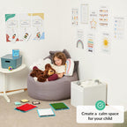 Child sitting on a bean bag in a room with educational posters and toys, promoting a calm space for children.