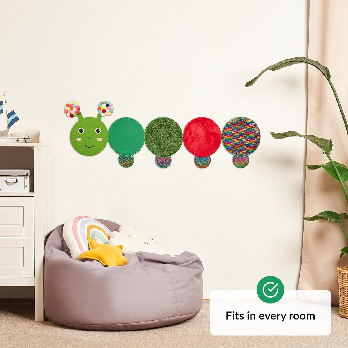 Colorful caterpillar wall decal above a bean bag chair in a room.