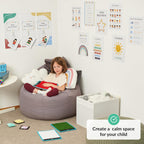 Child sitting on a bean bag in a room with educational posters and toys, promoting a calm space for children.
