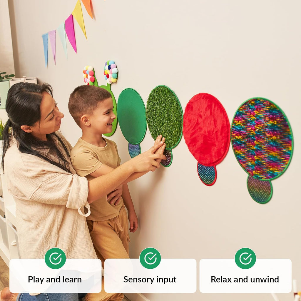 Woman and child interacting with caterpillar turtle-shaped wall decorations on a light-colored wall.