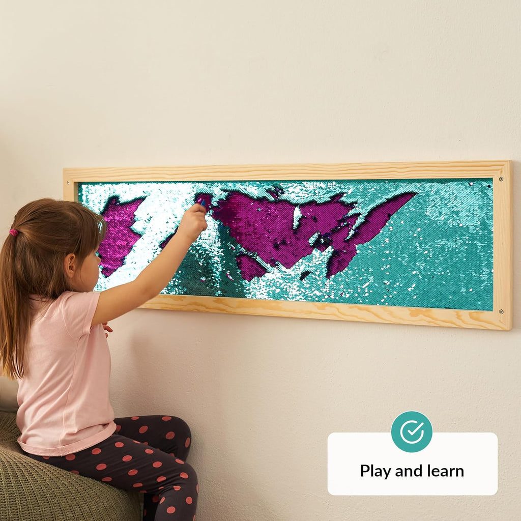 Child interacting with a colorful sequins wall on a wall, with a 'Play and learn' label.