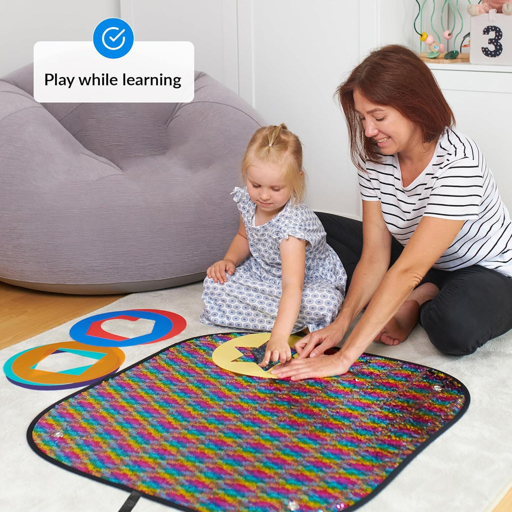 Woman and child playing with a colorful learning sequins mat on the floor.