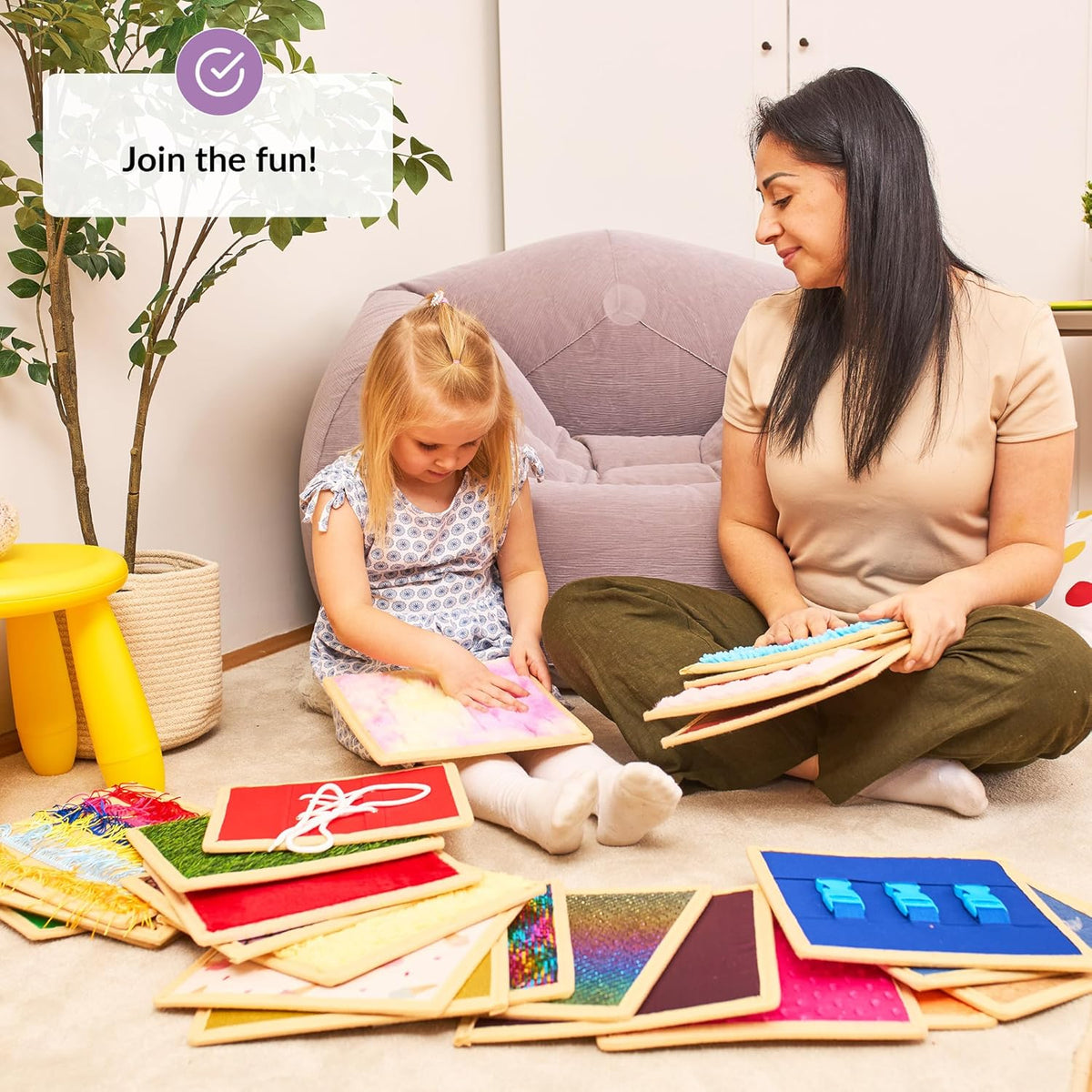 Woman and child playing with educational sensory tiles on the floor.