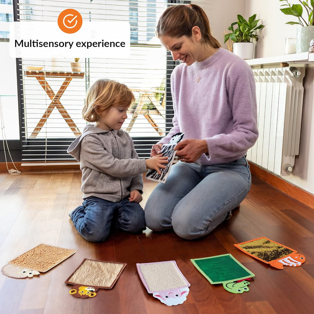 Woman and child sitting on a wooden floor with educational sensory mats, indoors.