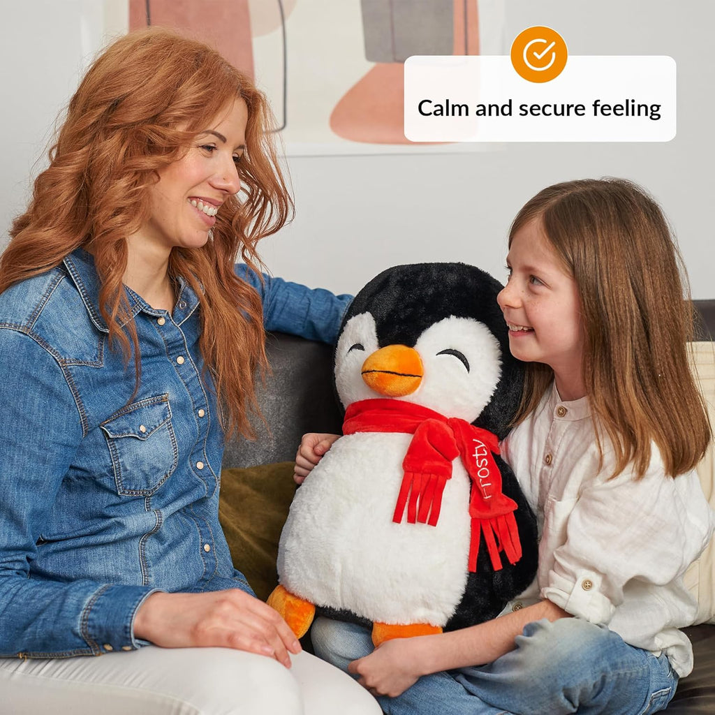 Woman and child holding a weighted plush penguin toy with a red scarf, sitting on a couch.