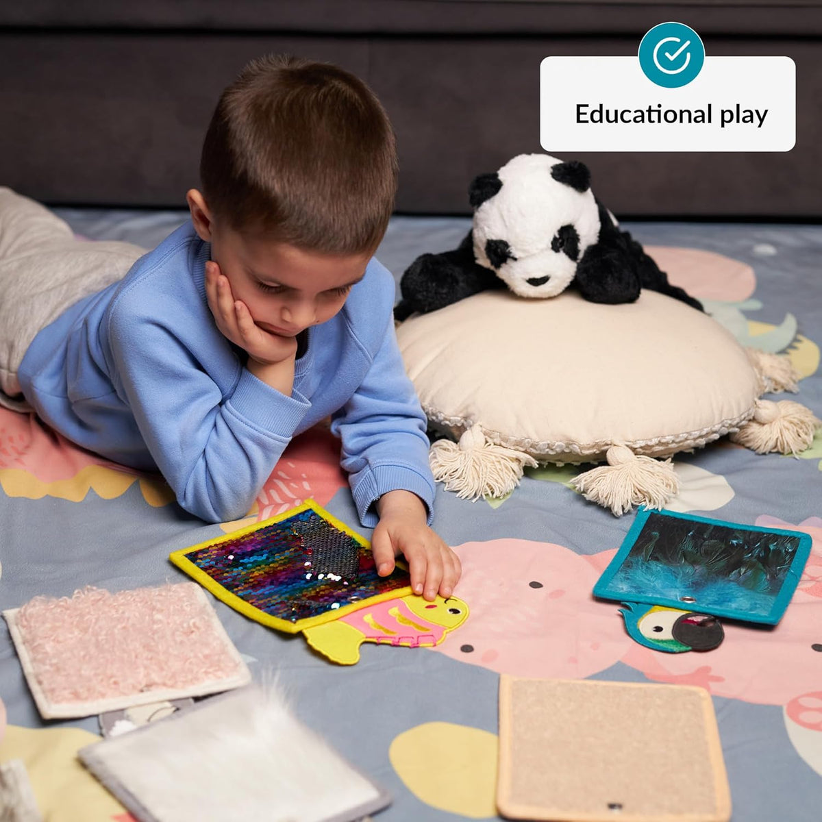 Child playing with educational sensory toys on a colorful mat, with a plush toy nearby.
