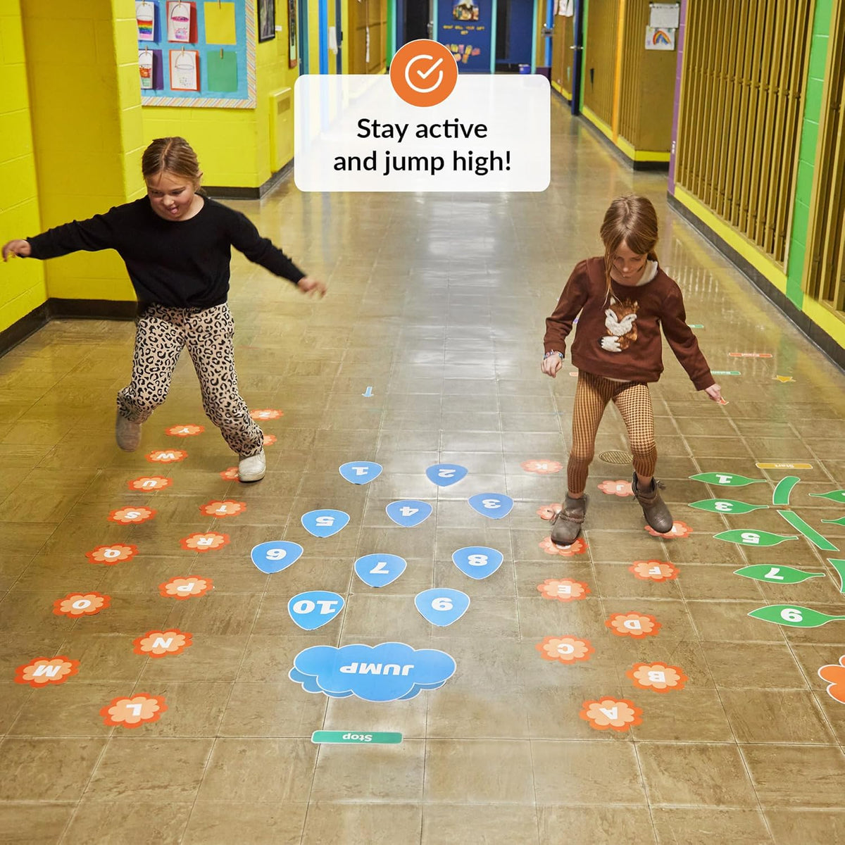 Two children playing on a floor with colorful markers in a classroom setting.