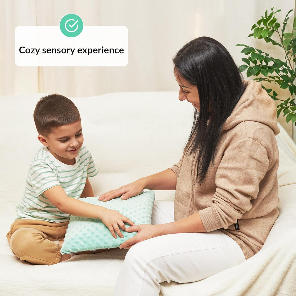Woman and child sitting on a couch with a sensory pillow, labeled 'Cozy sensory experience'.