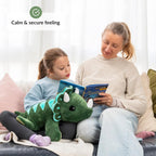 Woman and child reading a book together on a couch with a weighted dinosaur plush toy.