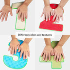 Four hands interacting with number-shaped sensory panels in different colors and textures on a white background.