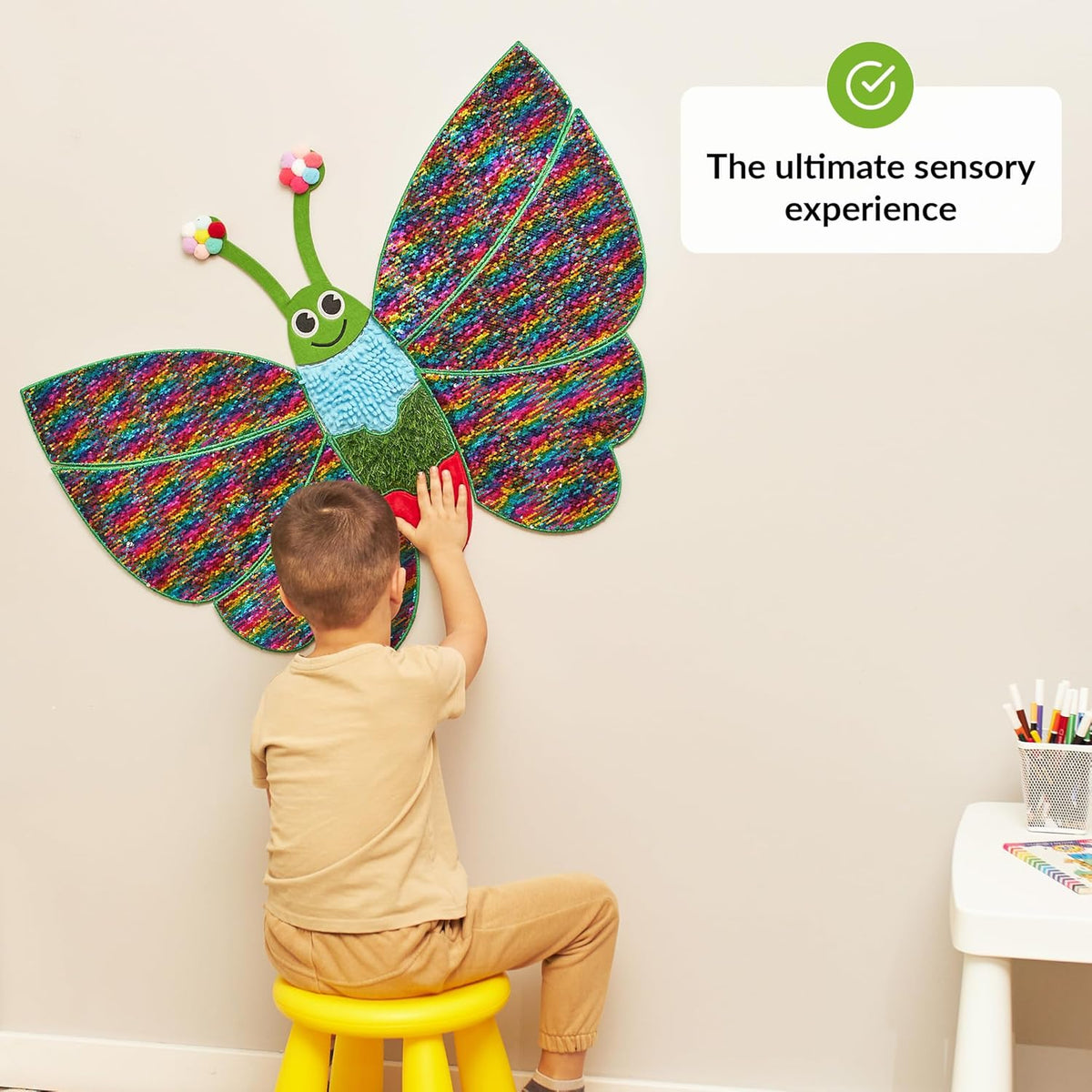 Child playing with a colorful butterfly-shaped wall decoration indoors.