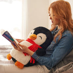 Woman reading a book to a large weighted plush penguin toy