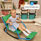 Child sitting on a green and blue sensory chair in a playroom with toys.