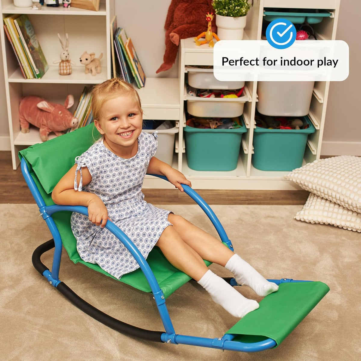 Child sitting on a green and blue sensory chair in a playroom with toys.