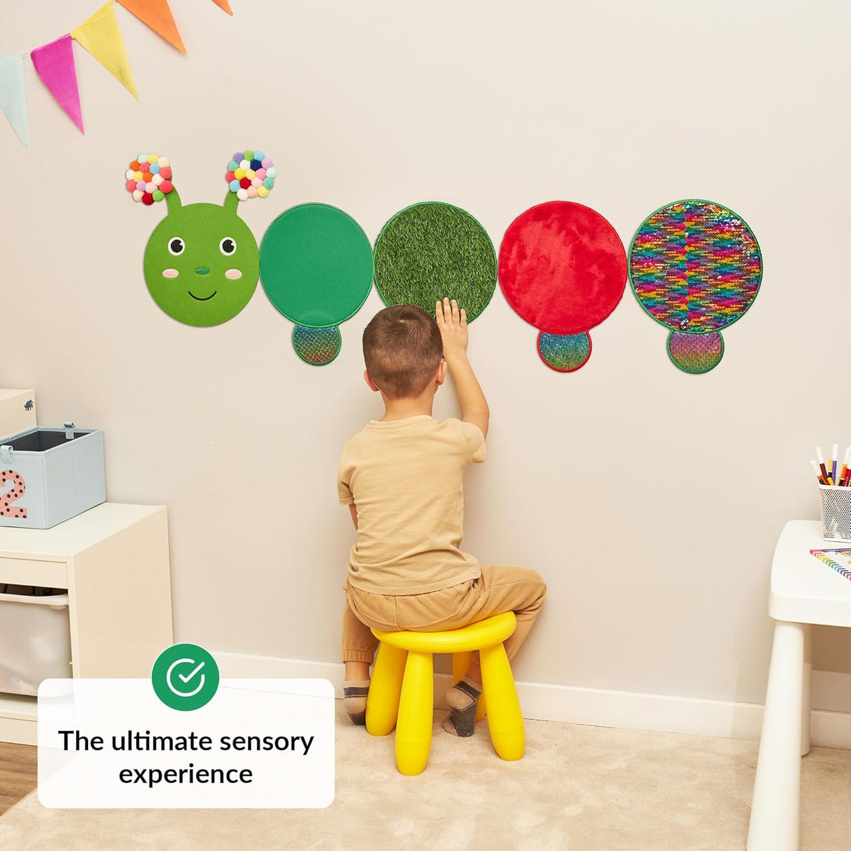 Child interacting with colorful wall-mounted caterpillar toy in a child-friendly room.