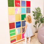 Child interacting with a colorful wall panel display in a room.