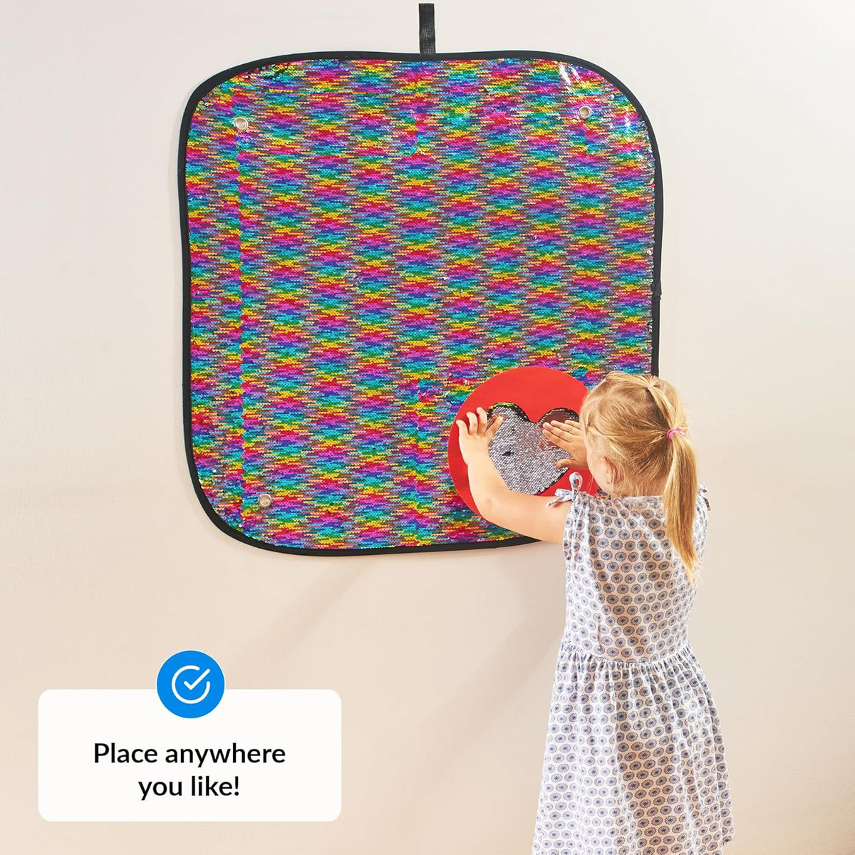 Child playing with a colorful patterned wall panel on a wall